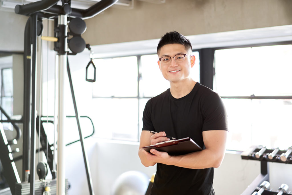 Asian male personal trainer taking notes of client's fitness goals and information